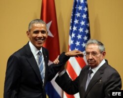 Raúl Castro levanta el brazo a Obama tras finalizar la conferencia de prensa.