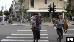 Una pareja israelí corre tras escuchar las sirenas de alarma en Tel Aviv, Israel. Archivo. 