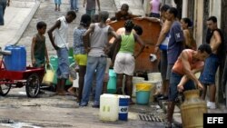 Varias personas esperan su turno para abastecerse del agua depositada en un tanque. 