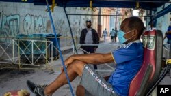 Un taxista en bicicleta espera clientes afuera de una vivienda, en La Habana, donde la policía controla el acceso a un vecindario. (AP/Ramon Espinosa)