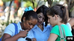 Jóvenes utilizan sus teléfonos celulares.