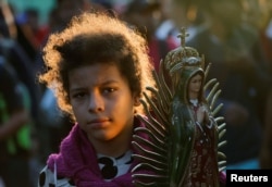 La venezolana Darlyn Mejía, de 13 años, lleva una figura de la Virgen de Guadalupe mientras camina con su familia en caravana durante el día de las elecciones presidenciales de EEUU, en un intento de llegar a la frontera norte de México, en Tapachula. (REUTERS/Daniel Becerril)