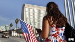 Una mujer camina con una bandera de EE.UU. frente a la embajada de ese país en La Habana