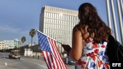 Una mujer camina con una bandera de EEUU frente a la embajada de ese país en La Habana.